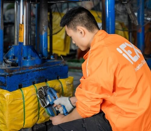 Operario de Indetexx comprimiendo y flejando una paca para exportación